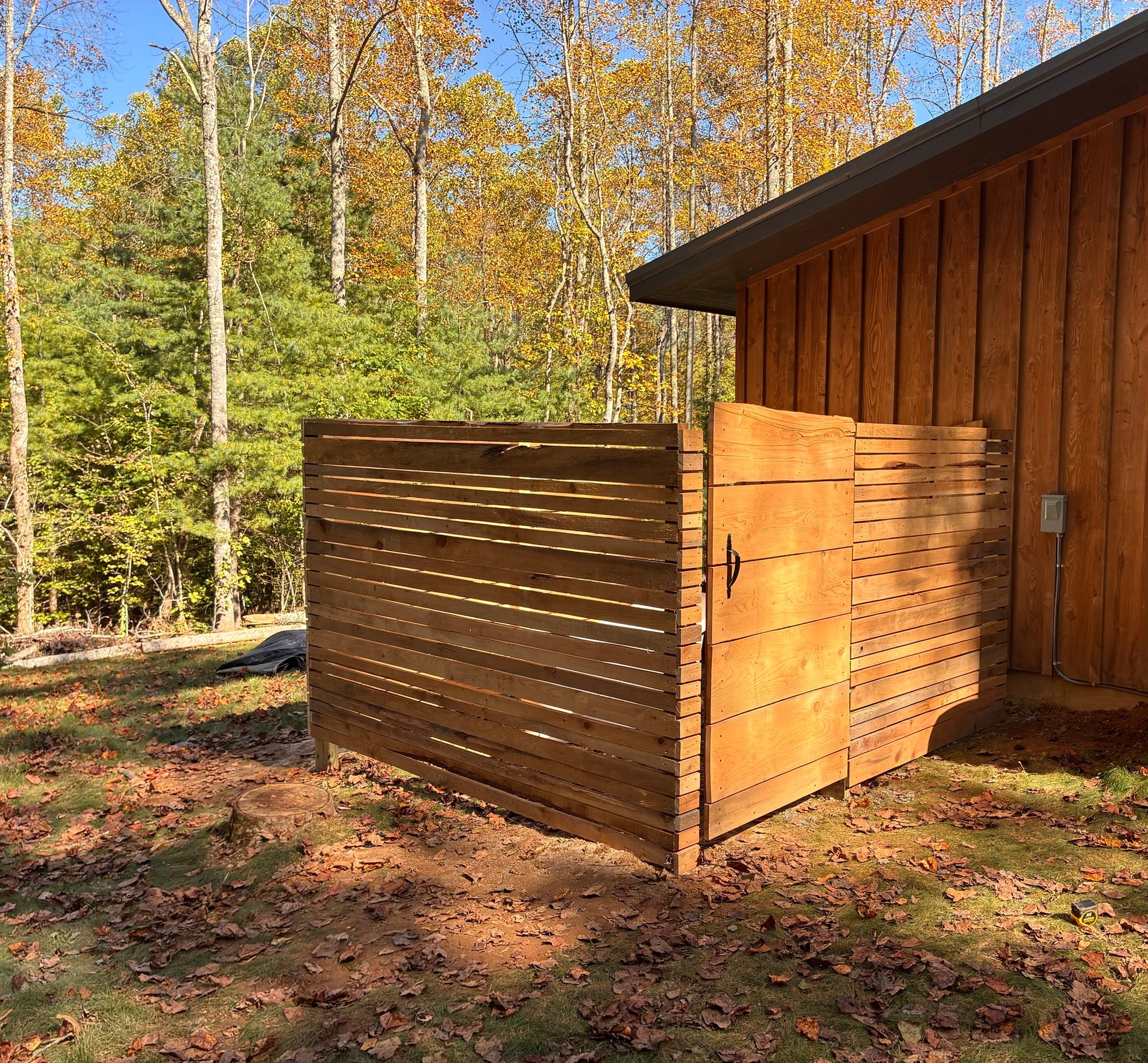 Outdoor shower enclosure with horizontal wood slats and a matching wood gate