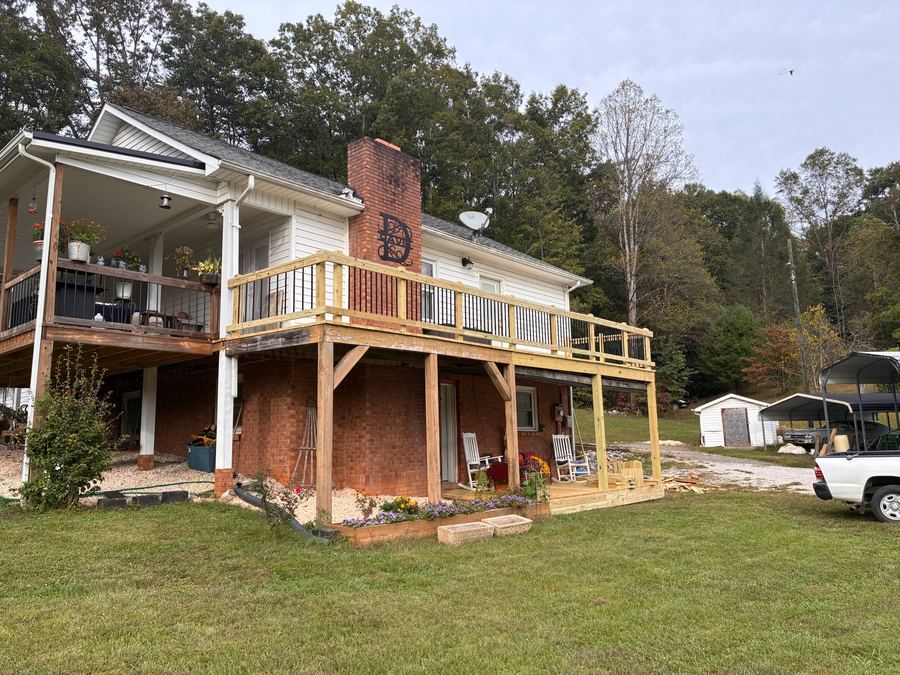Second-story deck with a wood rail and black balusters above a new covered porch